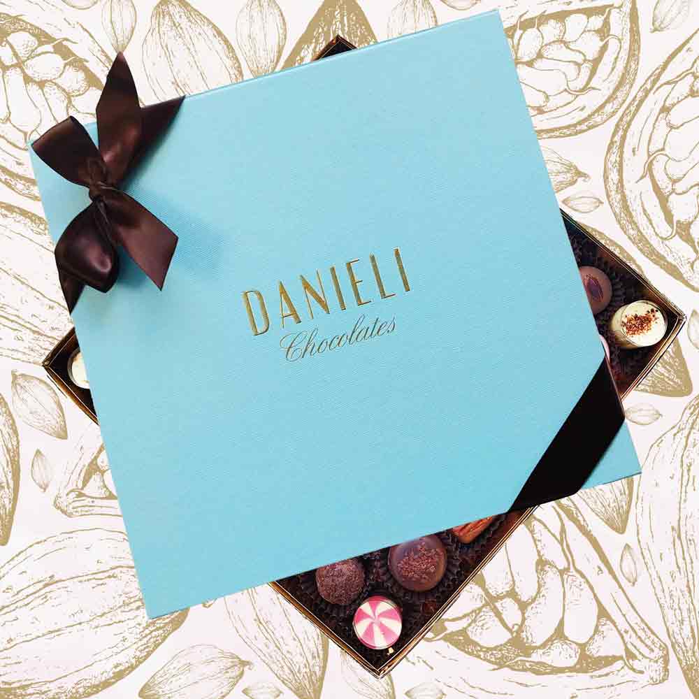Blue box of Danieli Chocolates with a brown ribbon on a decorative background