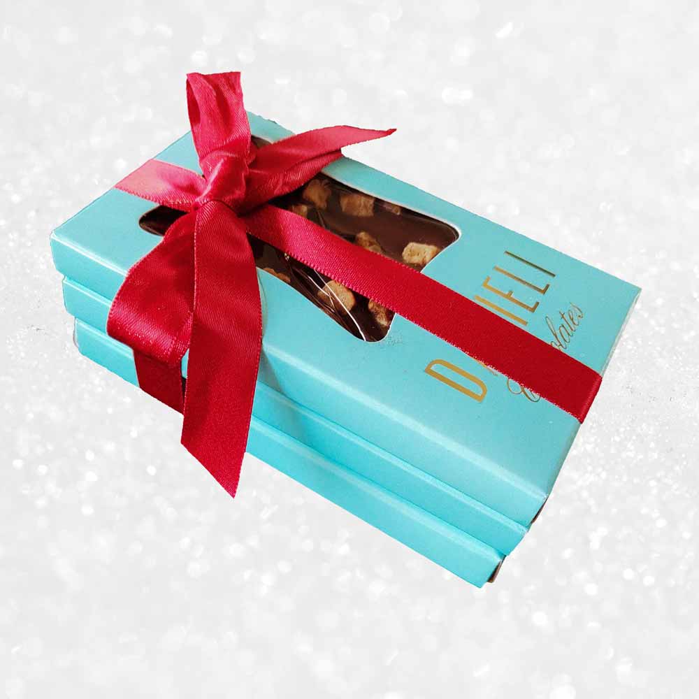 side view of gift pack of three danieli chocolate bars on a snowy background