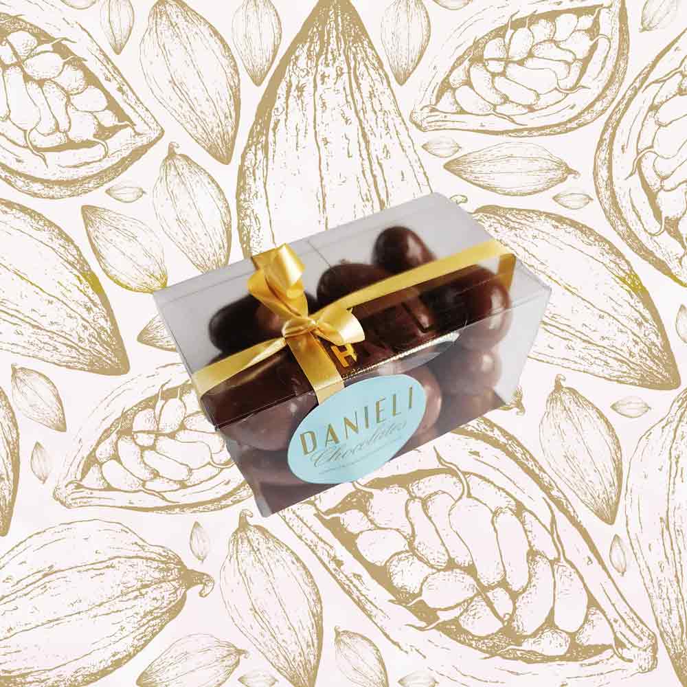 side view of a gift box of Danieli milk chocolate brazils on a cacao background