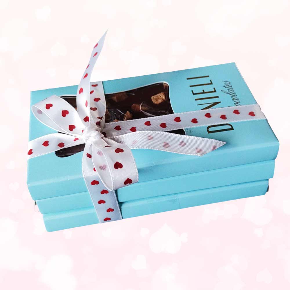 side view of gift pack of three danieli chocolate bars on a cacao background