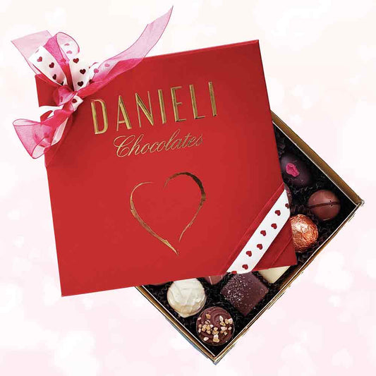 top view of a Danieli heart chocolate gift box with a heart ribbon on a pink background