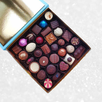 Blue box of Danieli Chocolates with a red ribbon on a decorative background