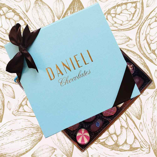 Blue box of Danieli Chocolates with a brown ribbon on a decorative background
