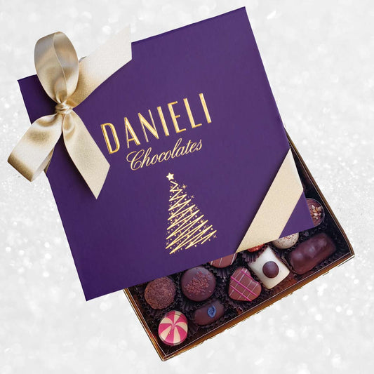 Box of Danieli Chocolates with a purple lid featuring a gold bow and Christmas tree design.