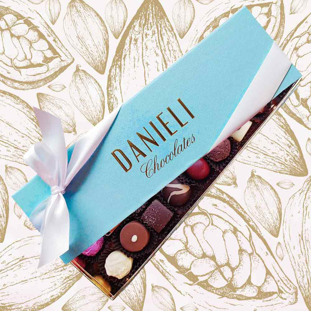 top view of a Danieli chocolate gift box with 18 chocolates with a white satin ribbon on a cacao pod background