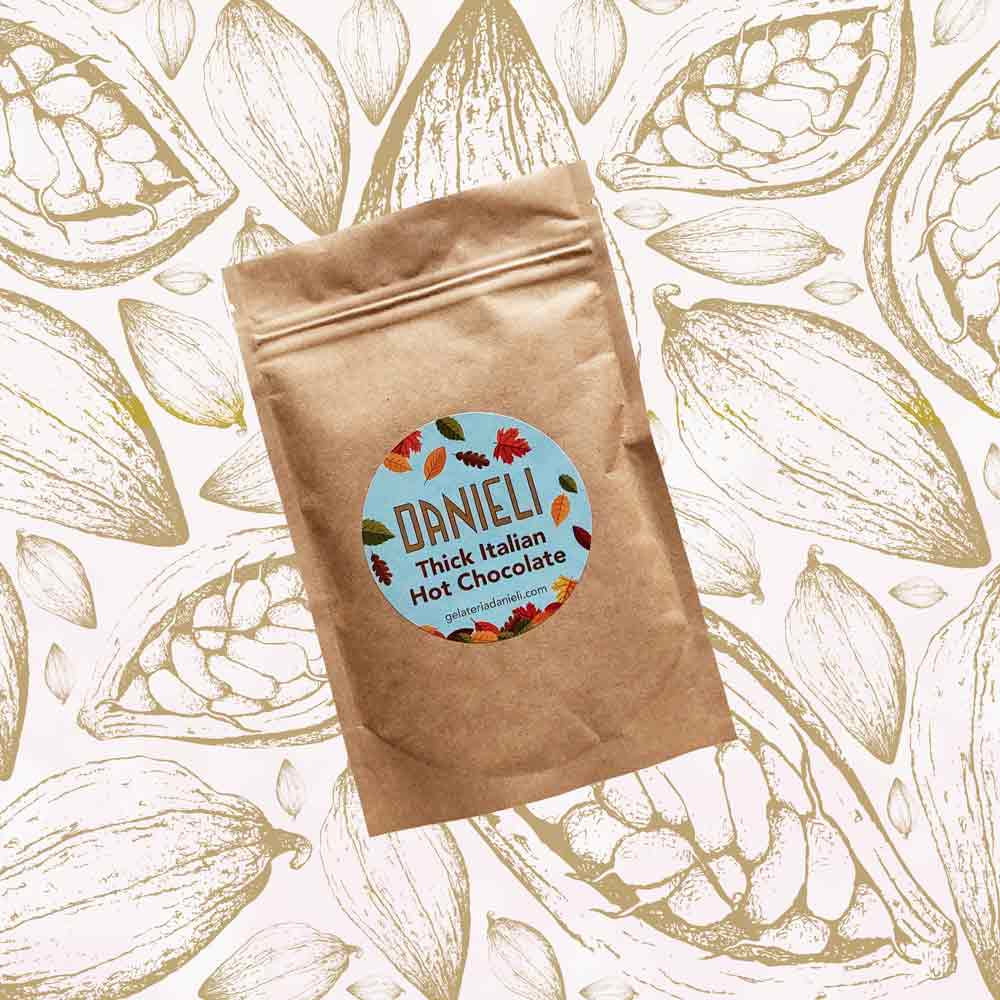 front view of Danieli luxury hot chocolate 100g pouch autumn edition on a cacao pod background