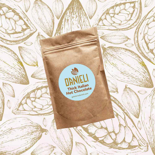 front view of Danieli luxury hot chocolate 100g pouch classic edition on a cacao pod background