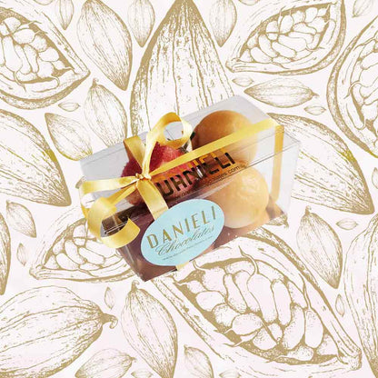 side view of a gift box of Danieli marzipan fruits on a cacao pod background