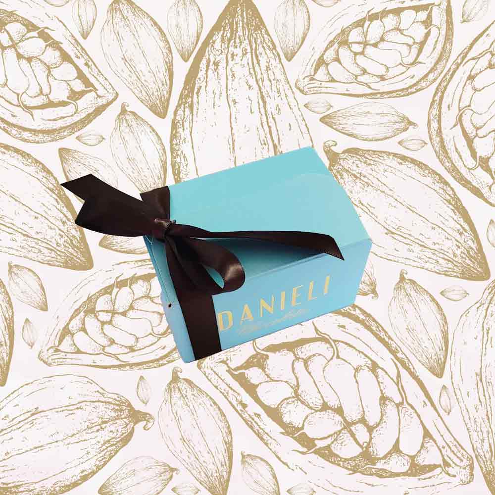 Blue chocolate gift box with brown ribbon on a background with cocoa bean illustrations