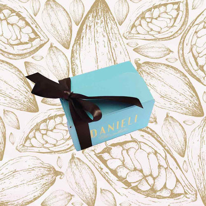 Blue chocolate gift box with brown ribbon on a background with cocoa bean illustrations