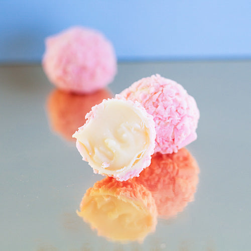 White chocolate pink champagne truffle on a gold background