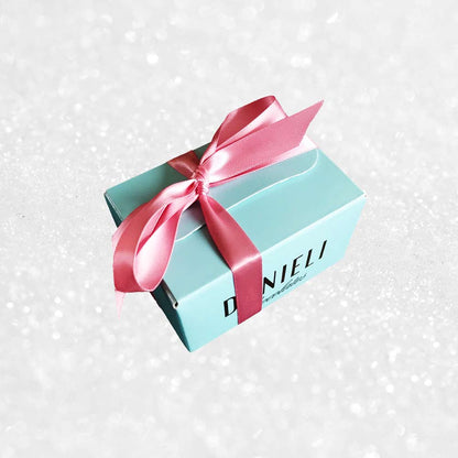 side view of a gift box of Danieli rose and violet chocolate creams on a snowy background