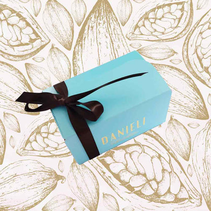 top view of a Danieli chocolate gift box small ballotin with a brown satin ribbon on a cacao background