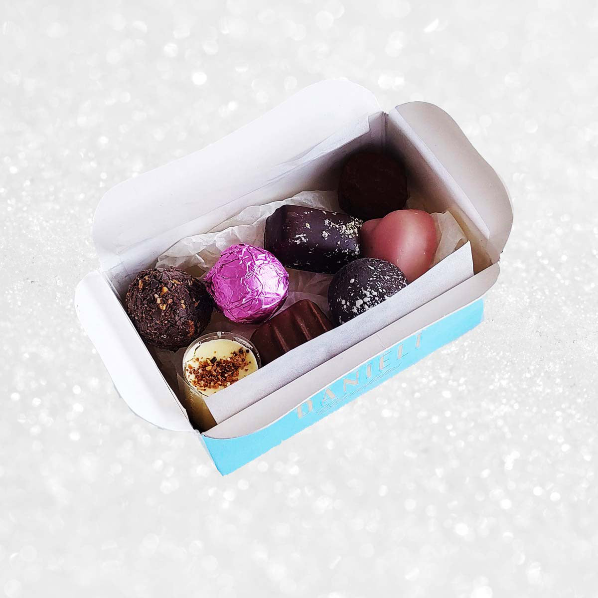 Assorted chocolates in a small open box on a white background