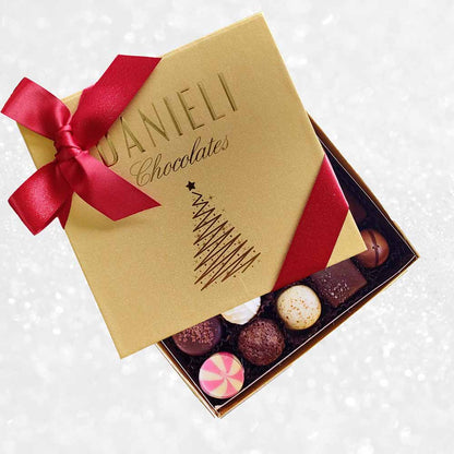 top view of Danieli chocolates for Christmas luxury gold box with a red ribbon on a snowy background