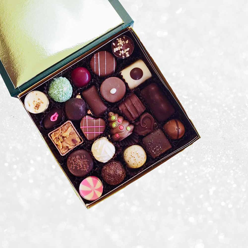 inside view of Danieli chocolates for Christmas luxury green box with a gold ribbon on a snowy background