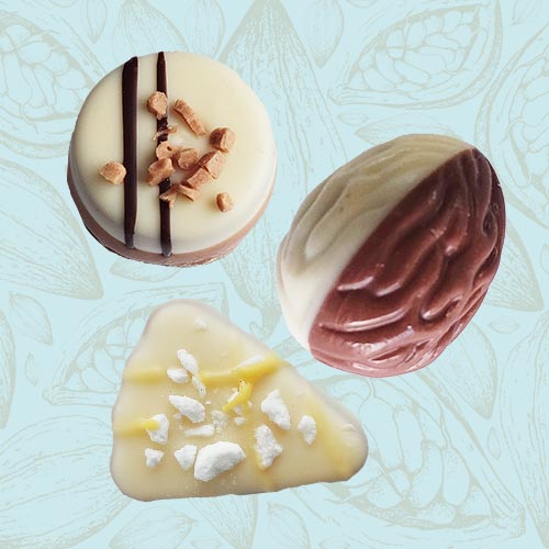 3 Danieli white chocolates on a blue and brown cacao pod background