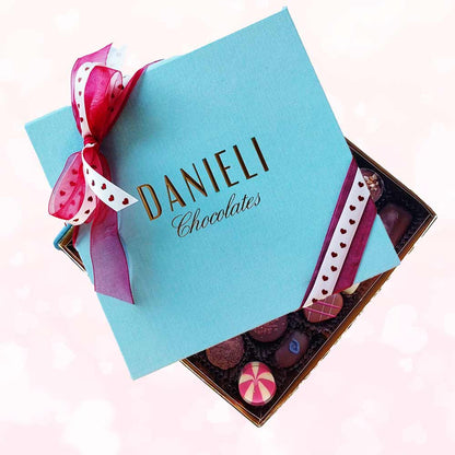 top view of a Danieli large chocolate gift box with a heart ribbon on a pink background