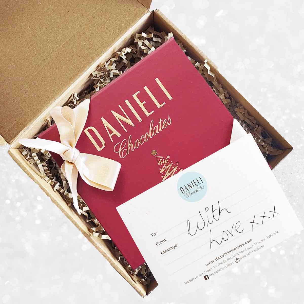 delivery box view of Danieli chocolates for Christmas luxury red box with a gold ribbon on a snowy background