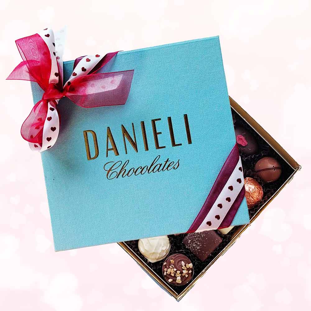 top view of a Danieli small chocolate gift box with a heart ribbon on a pink background