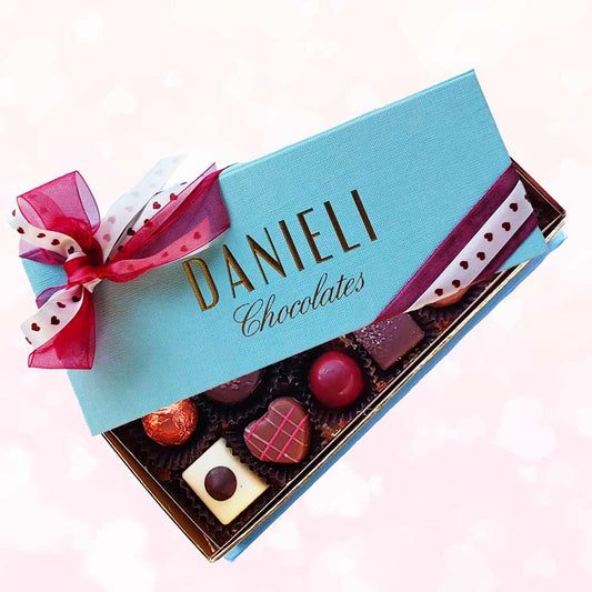 Chocolates for Valentines with 12 chocolates with a pretty pink and heart ribbon on a background of pale pink hearts