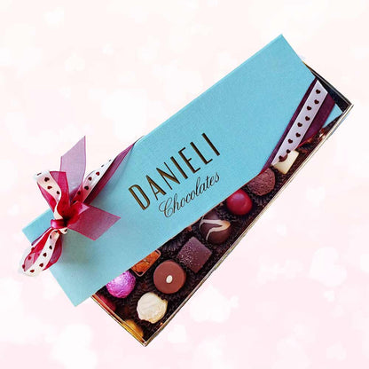 Chocolates for Valentines with 12 chocolates with a pretty pink and heart ribbon on a background of pale pink hearts